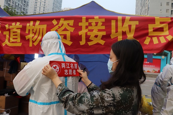 在北碚区蔡家岗街道两江名居，社区工作人员在给志愿服务队队员们粘贴标志。  通讯员 蒋弘程  摄