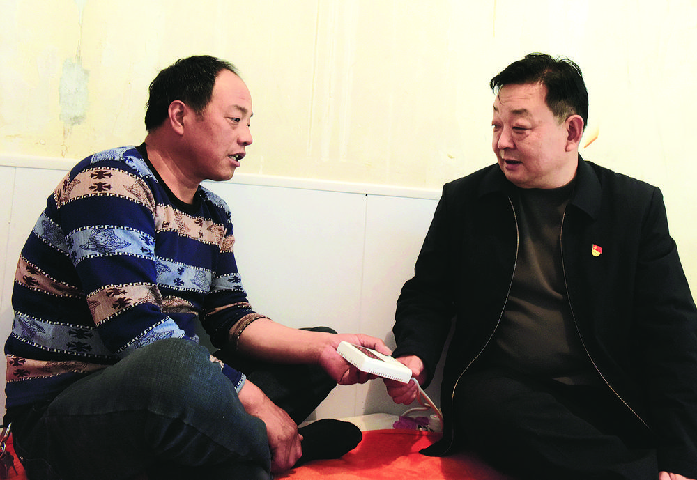 巨克毅（右）入户了解电热炕取暖情况。本报记者 李庆玲 摄